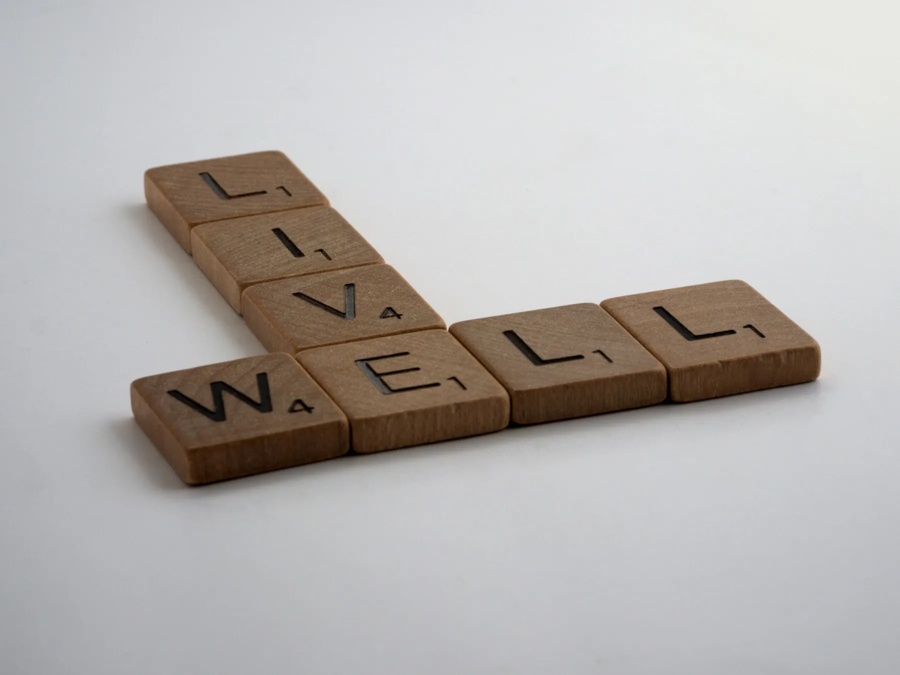 Wooden letter tiles spelling out "live well"